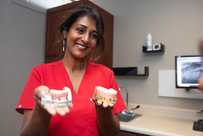 Doctor holding up model of full arch implants