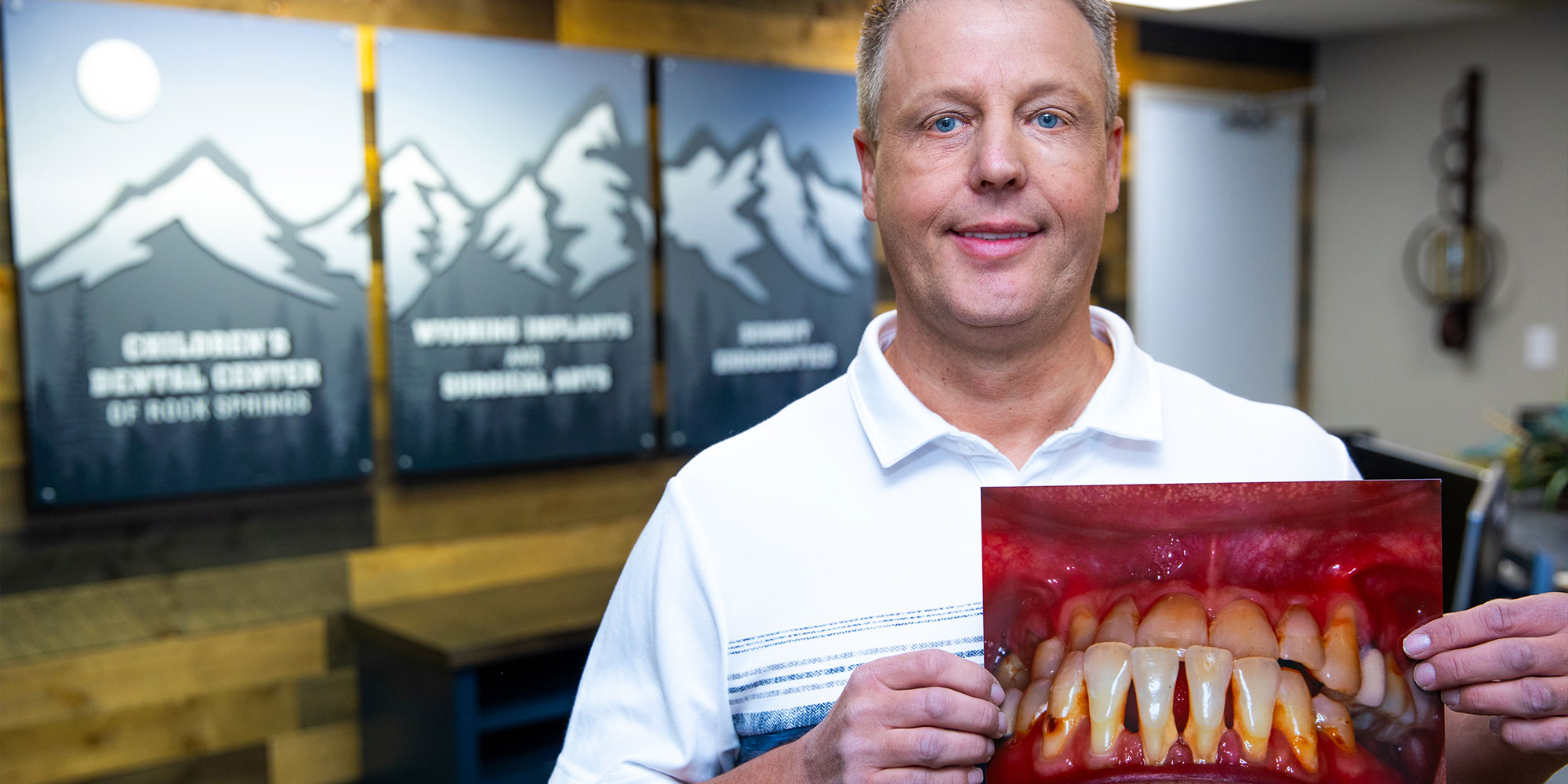 man holding a before and after photo of his teeth